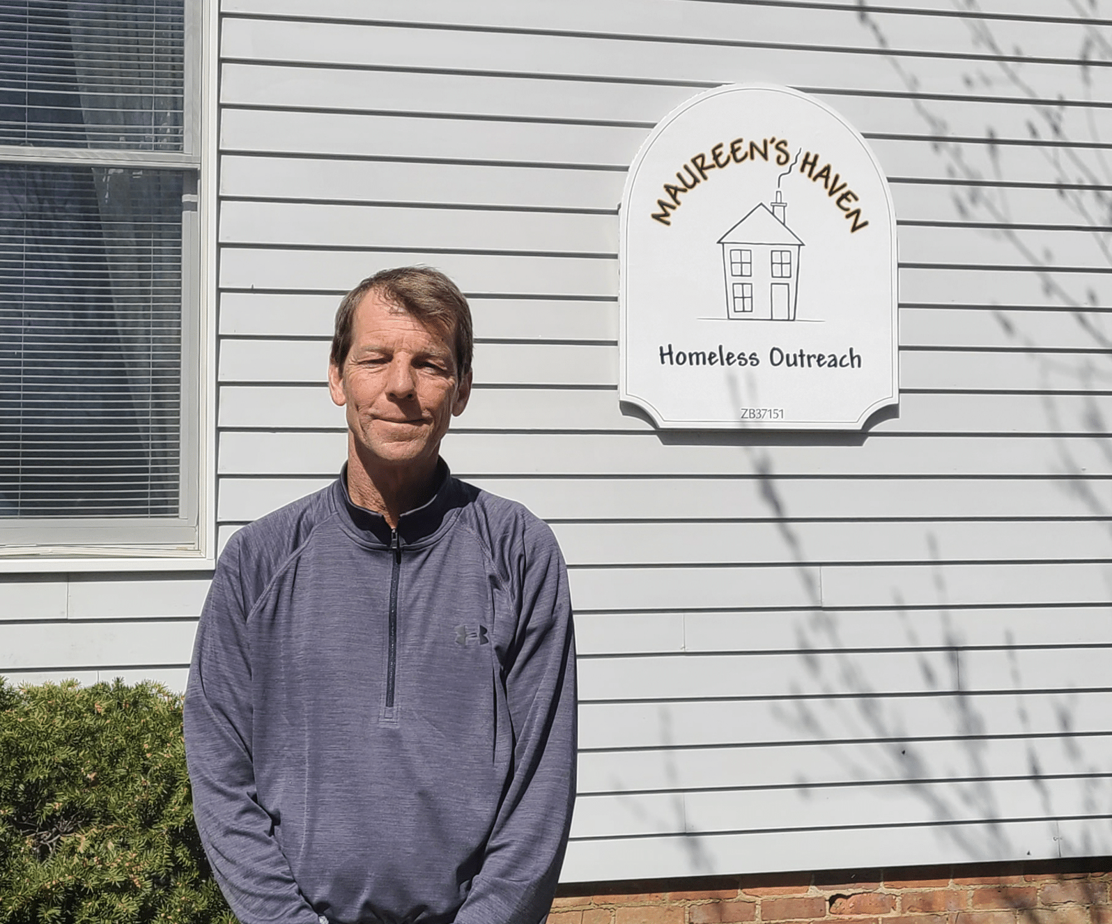 A man in front of a building with the sign